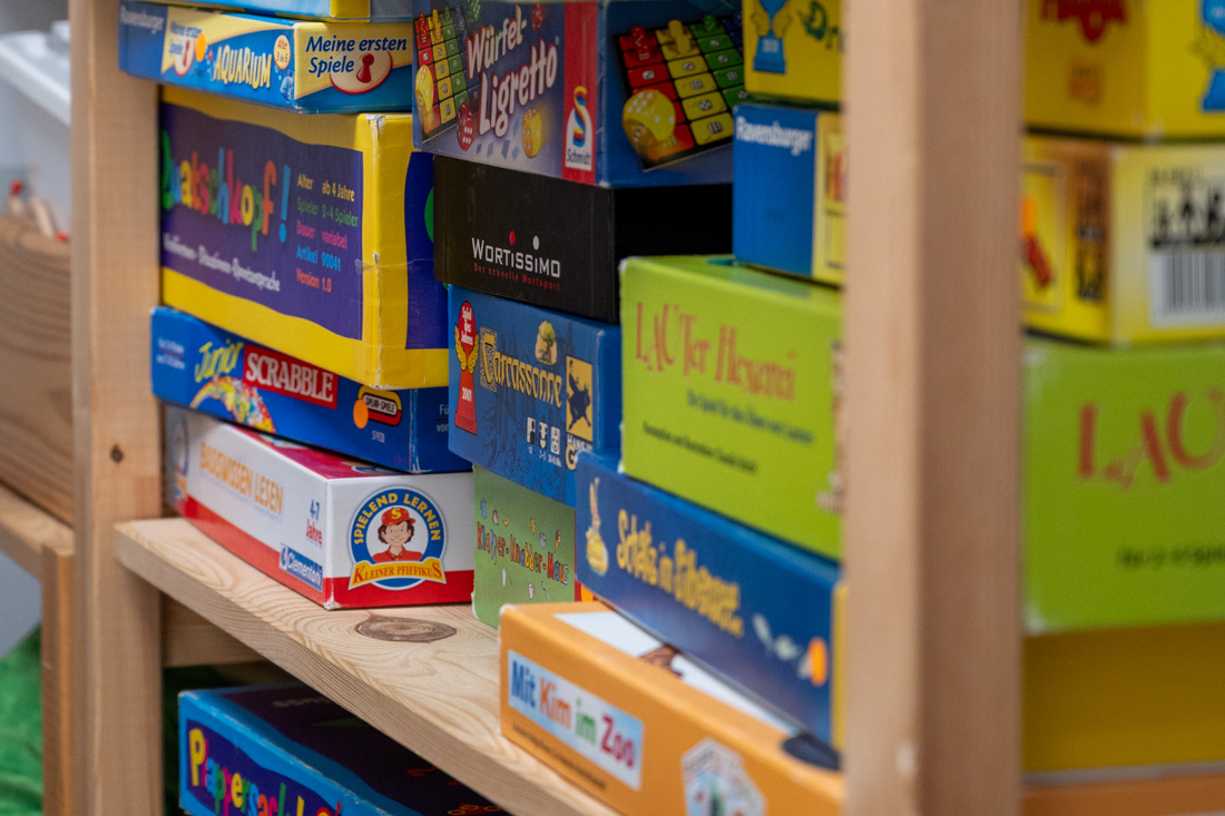 Ergotherapie für Kinder: Ein Kind fädelt gemeinsam mit einer Therapeutin Holzperlen auf eine Schnur